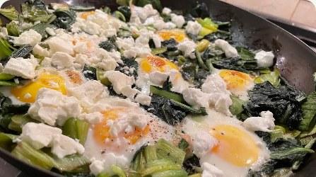 Skillet of greens with baked eggs and feta