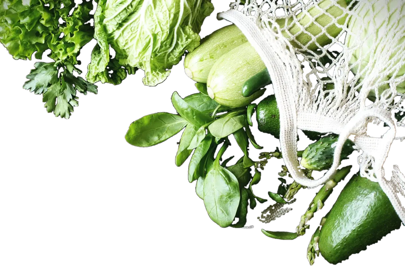 Fresh greens, zucchini, avocado and asparagus spilling from a mesh market bag
